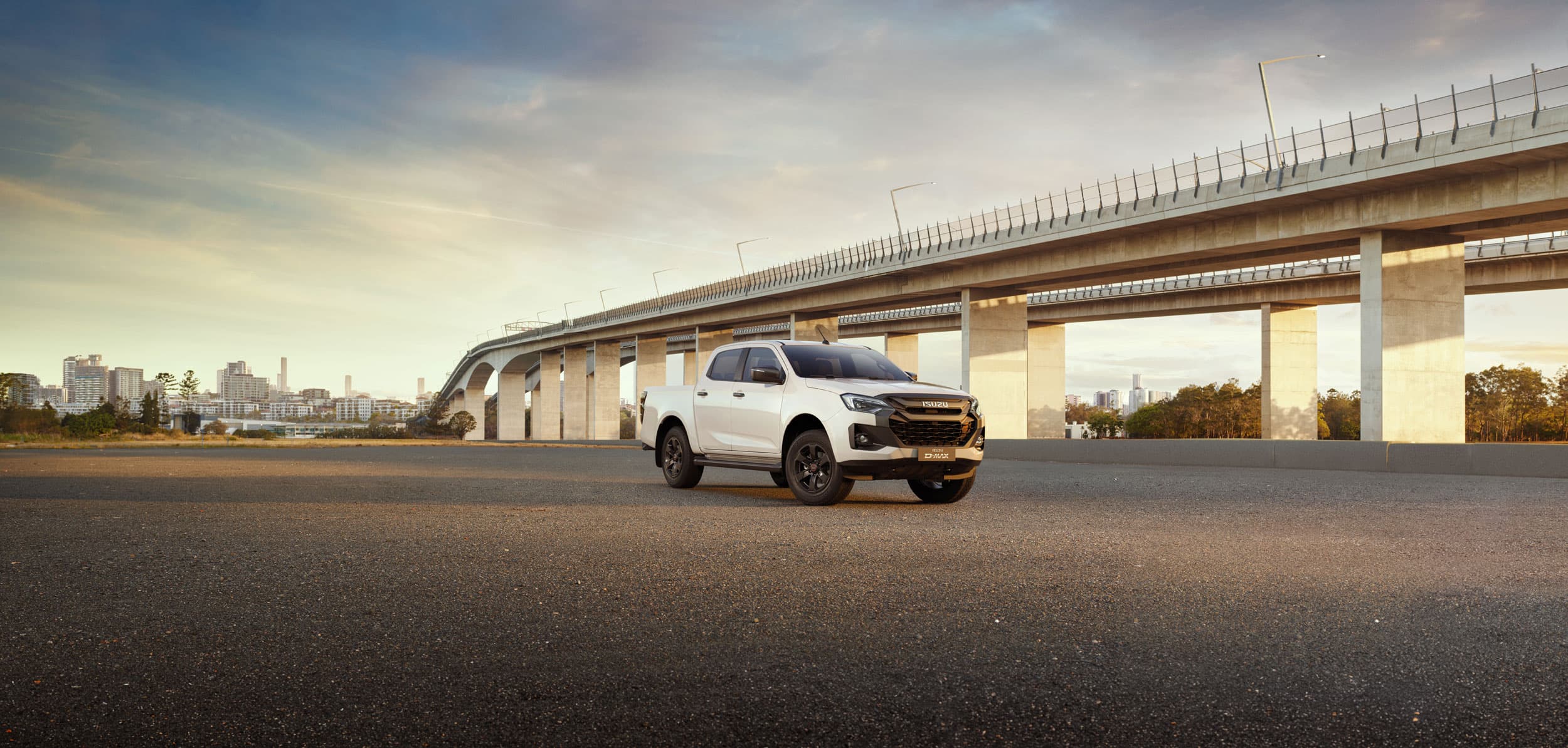Pearl white D-MAX oblique left view next to a bridge